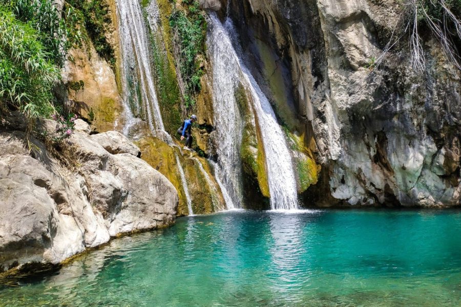 Barranquista saltando en una poza cristalina y turquesa junto a la cascada del barranco del Estret de les Penyes